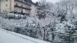 Een meerlaags gebouw met balkons, omgeven door met sneeuw bedekte bomen en struiken.