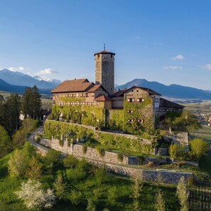A historic building with a tower, surrounded by lush greenery and mountains in the background. - Cozy apartment with garden - dogs welcome - Brenta Dolomites (Sarnonico)