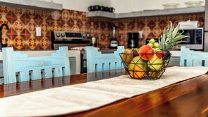 A dining table with a fruit bowl in the center, surrounded by blue chairs. - Babylon Beach Villa 8    (San Pedro)