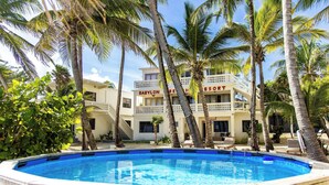 A pool surrounded by palm trees and a building labeled "BABYLON BEACH RESORT". - Babylon Beach Villa 8    (San Pedro)