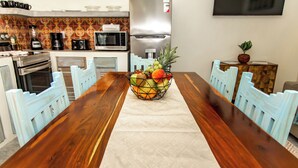 A wooden dining table with a fruit basket in the center, surrounded by light blue chairs. - Babylon Beach Villa 8    (San Pedro)