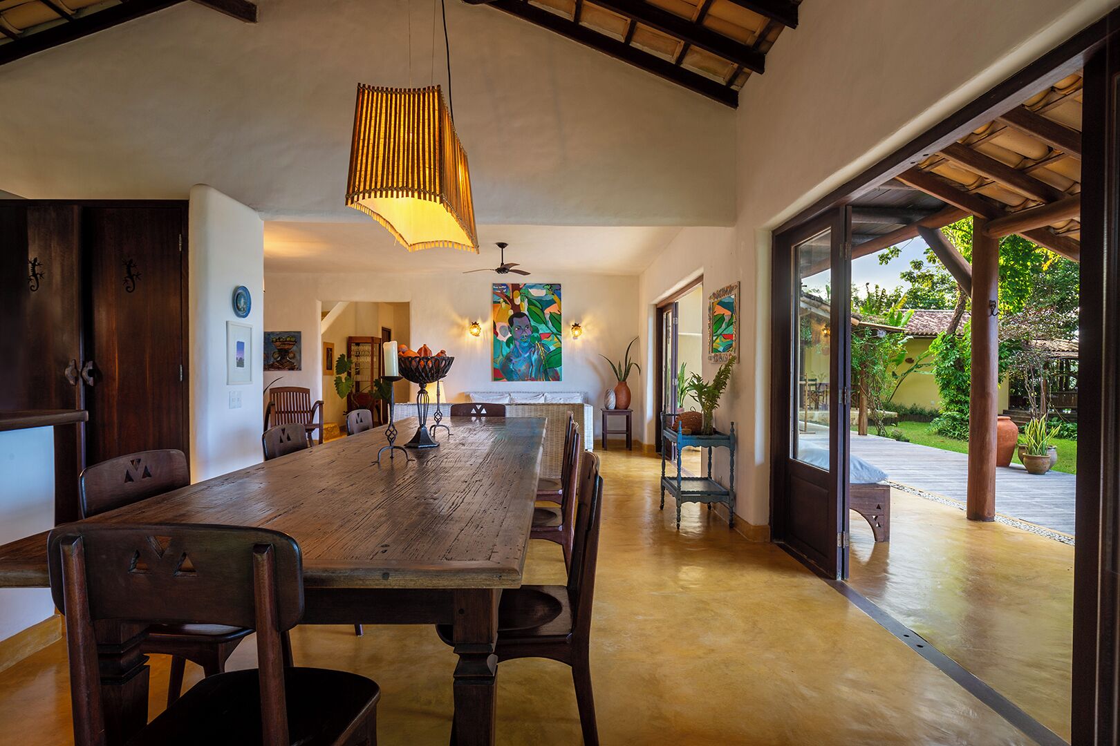 A spacious dining area with a long wooden table, chairs, and a hanging light fixture.