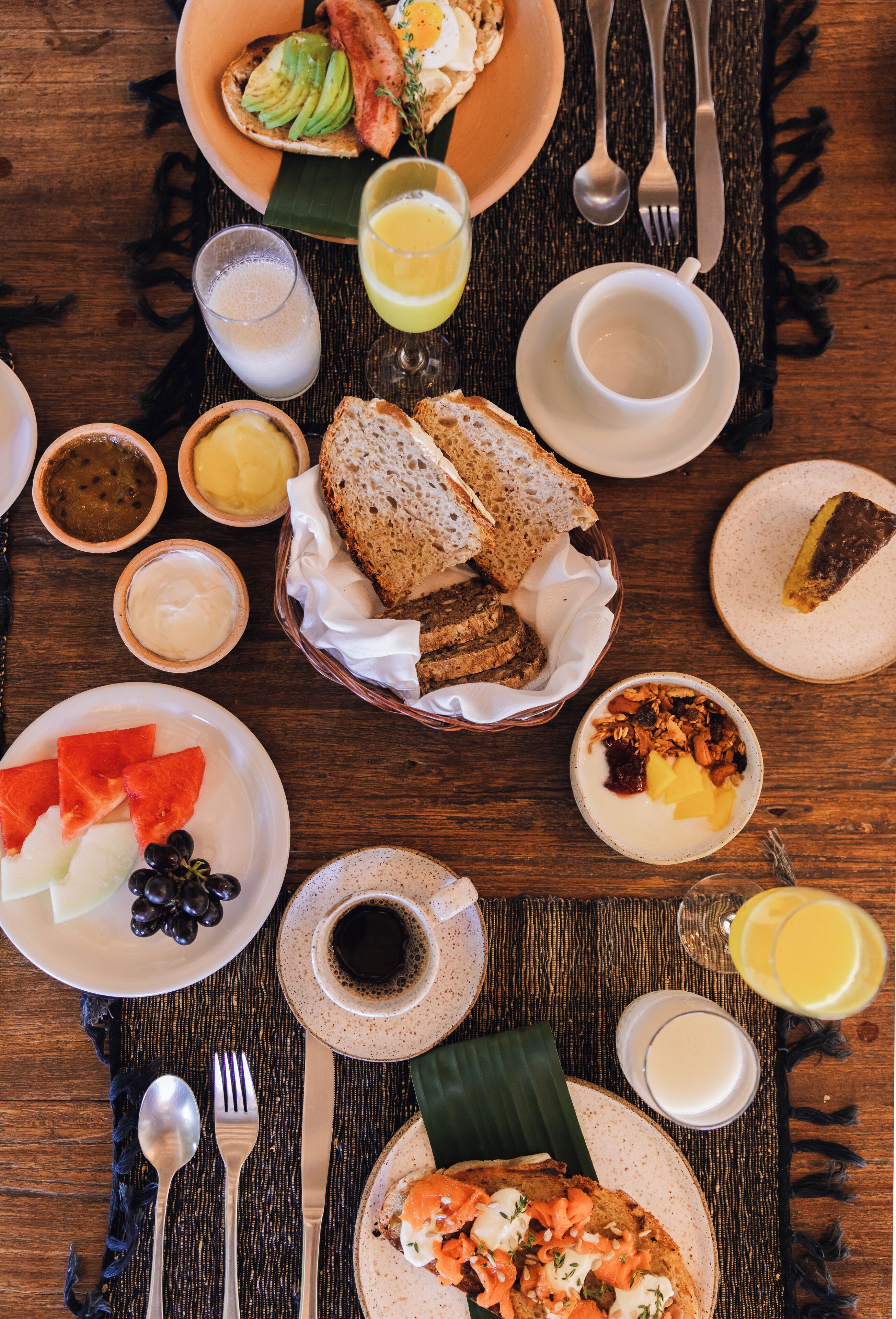 A breakfast setting with various dishes, including toast, fruit, and beverages.