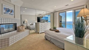 Une chambre avec un grand lit, une télévision, une commode et une vue sur la mer.
