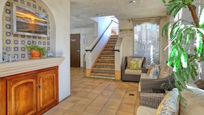 A spacious living area with a staircase, a sofa set, and a potted plant. - Ocean-View Luxury at Valentina Suites - Suite 201 (Pismo Beach)