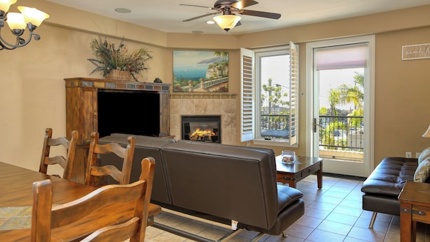A living room with a fireplace, a ceiling fan, and a view of the outdoors. - Ocean-View Luxury at Valentina Suites - Suite 201 (Pismo Beach)