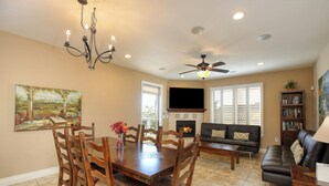 A dining area with a wooden table and chairs, a chandelier, and a fireplace.