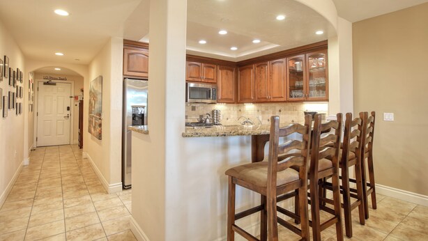 A kitchen with wooden cabinets, a granite countertop, and a built-in island with bar stools.