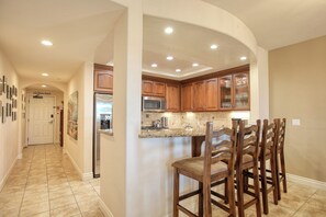 A kitchen with wooden cabinets, a granite countertop, and a built-in island with bar stools.