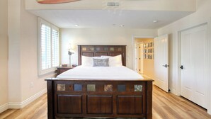 Un dormitorio con cama de madera, una mesita de noche, una lámpara y una ventana con persianas.