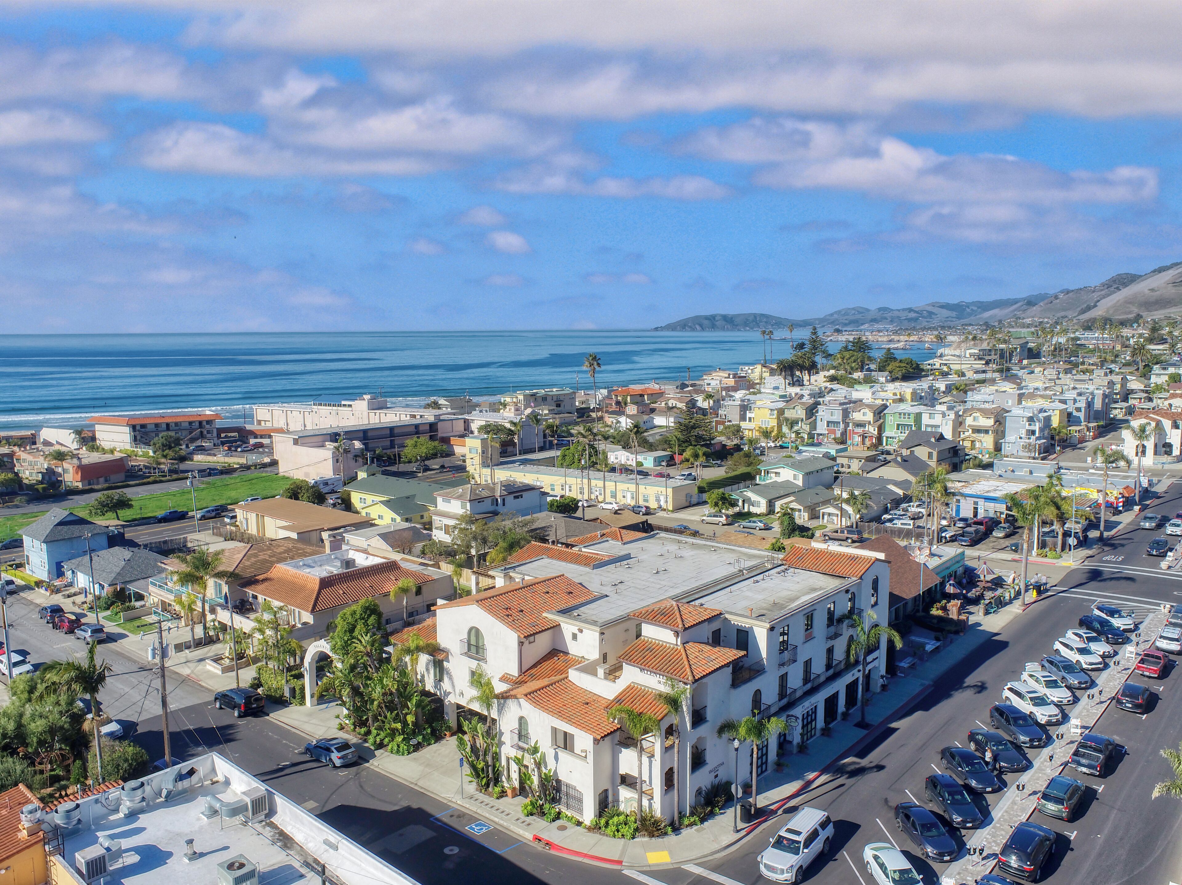 A coastal town with a mix of residential and commercial buildings, a parking lot, and a view of the ocean.