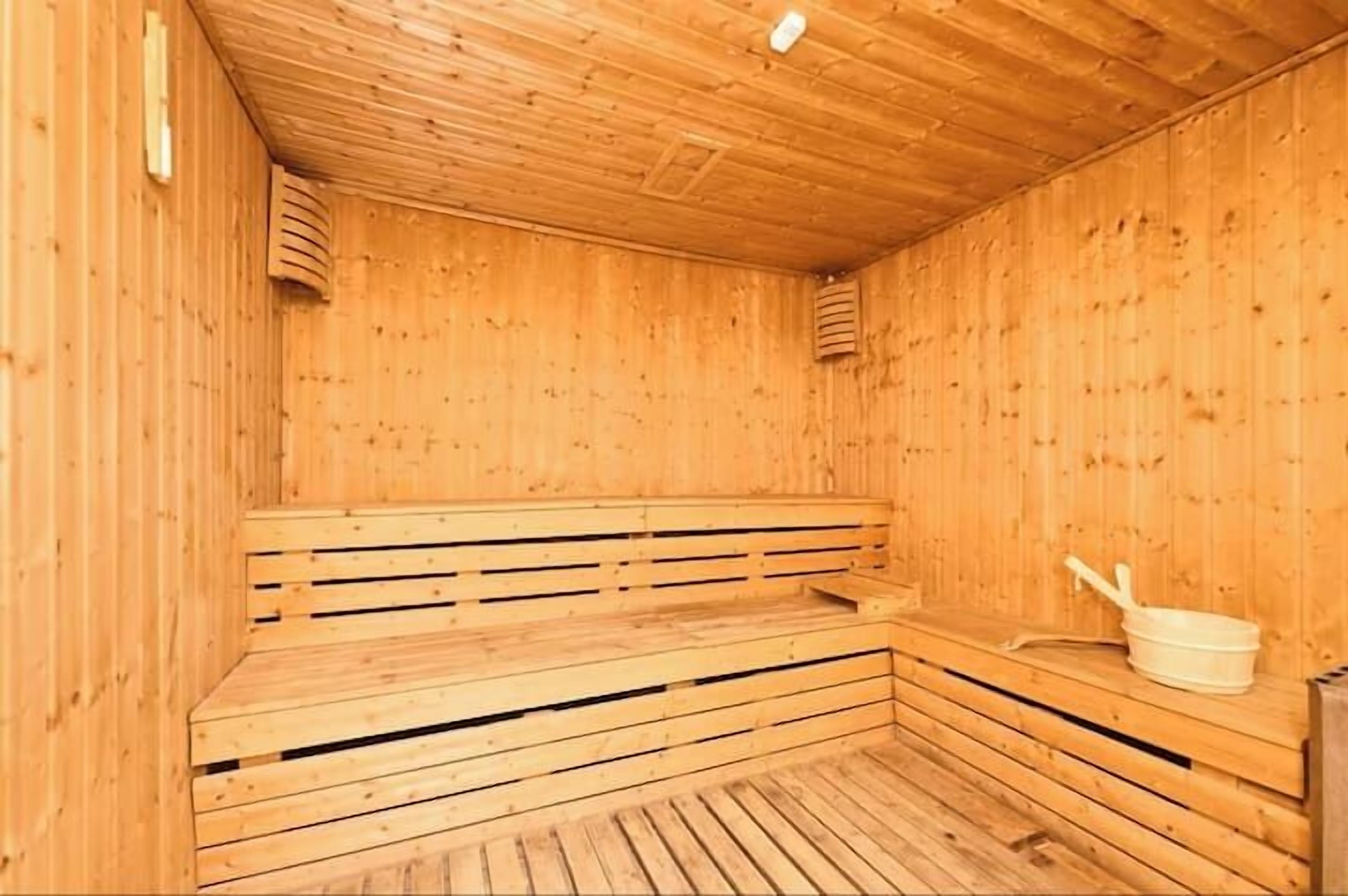 A wooden sauna with benches and a bucket.