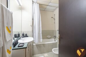 A bathroom with a bathtub, a shower, and two sinks. - Vogue | Lake City Tower JLT near Marina | JBR (Dubai)
