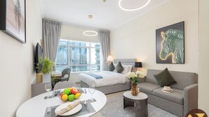 Une chambre d’hôtel moderne avec un lit, un canapé, une table à manger avec des fruits et une vue sur la ville.