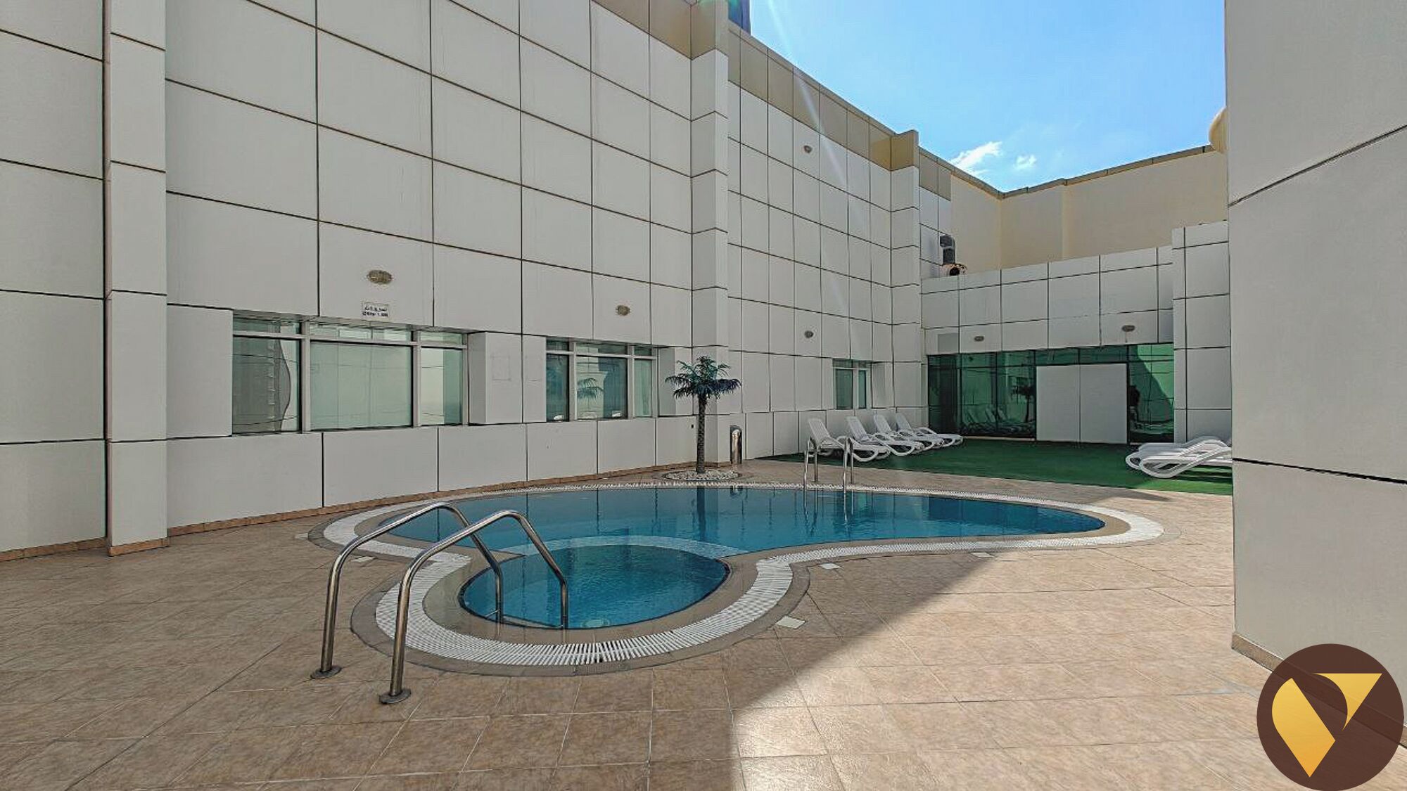 A modern indoor pool area with a clear blue pool, sun loungers, and a tiled floor.
