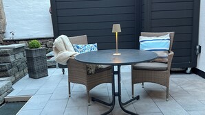 A round table with two wicker chairs, a lamp, and a small potted plant. - Marketplace atrium 1 on the ground floor (Höxter)