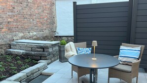 An outdoor patio with a round table and two wicker chairs, a small lamp, and a planter with a plant. - Marketplace atrium 1 on the ground floor (Höxter)