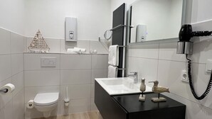 A modern bathroom with a black vanity, a toilet, a sink, and a mirror. - Marketplace atrium 1 on the ground floor (Höxter)