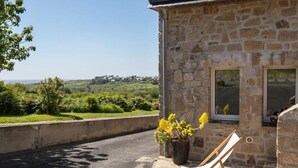 Il s'agit d'un bâtiment en pierre qui offre une vue sur la campagne. On y trouve une chaise et un pot de fleurs à l'extérieur.