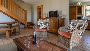 Un salon avec des meubles en osier, un escalier en bois et un téléviseur.