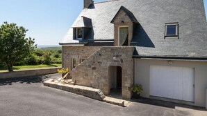 Un bâtiment en pierre avec un toit en pente, une petite entrée et une porte de garage.