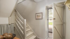 A staircase leading to a landing with a door, a framed picture on the wall, and a basket of items on a table. - Two bedroom Cottage in the heart of Beadnell (Beadnell)