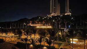 A nighttime view of a hotel with a large illuminated sign reading "APEC Mandala Hotel".
