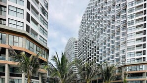 A modern outdoor seating area with a round table and chairs, surrounded by tall buildings and palm trees.