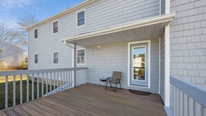A two-story house with a wooden deck and a covered porch. - 5 Bedroom Beach Retreat (Narragansett)