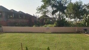 A grassy courtyard with potted plants and a bench. - Rani Kutir Resort (Bolpur)