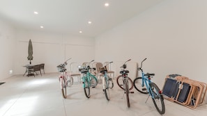 A spacious room with a tiled floor, a dining table with chairs, and a row of bicycles. - 126 Gulf Island Peaceful Pool Home near Beach (Fort Myers Beach)