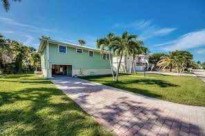 A single-story house with a paved driveway and a lawn, surrounded by palm trees. - 126 Gulf Island Peaceful Pool Home near Beach (Fort Myers Beach)