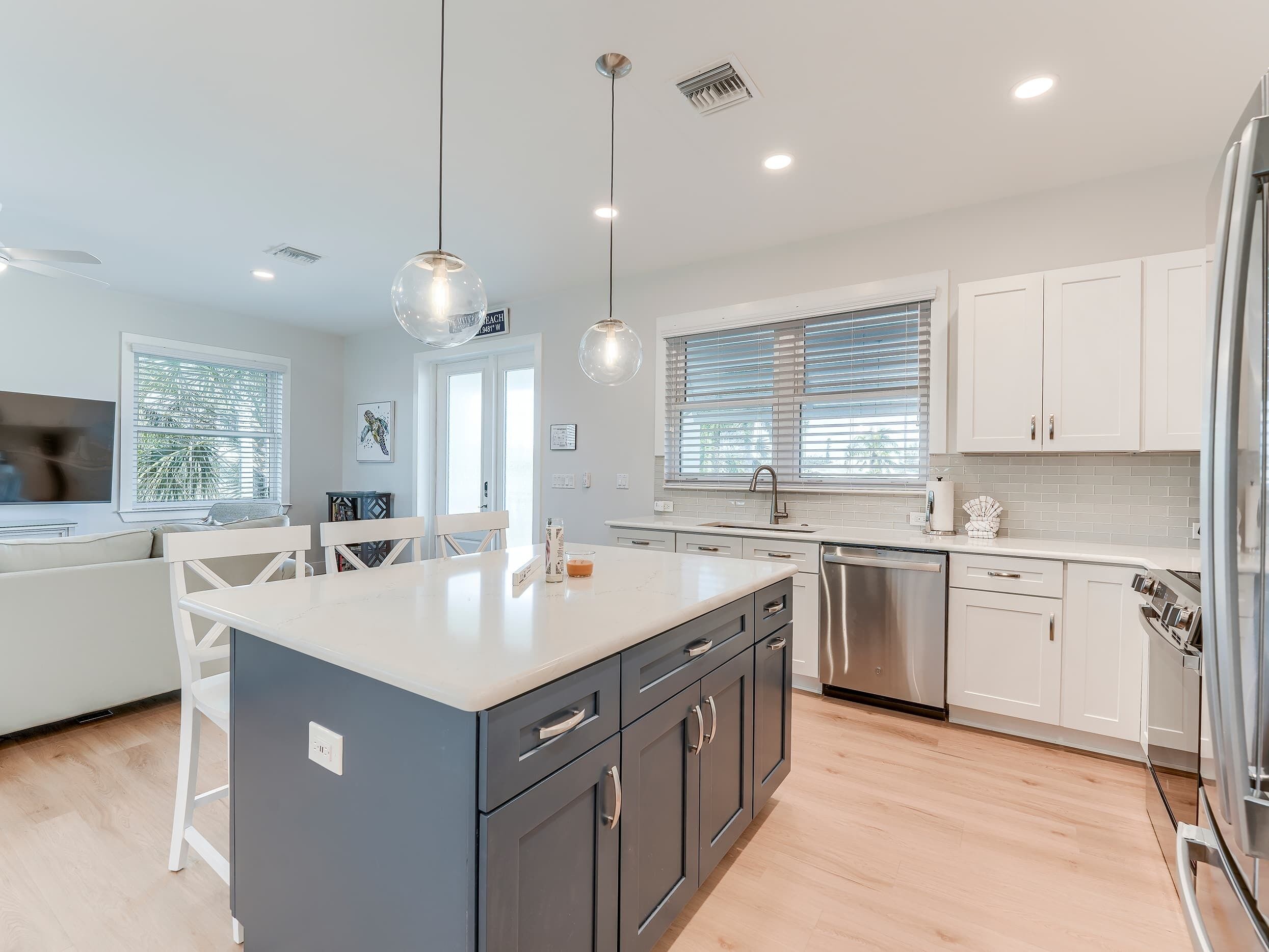 A modern kitchen with a central island, stainless steel appliances, and white cabinetry.