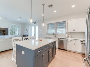 A modern kitchen with a central island, stainless steel appliances, and white cabinetry.