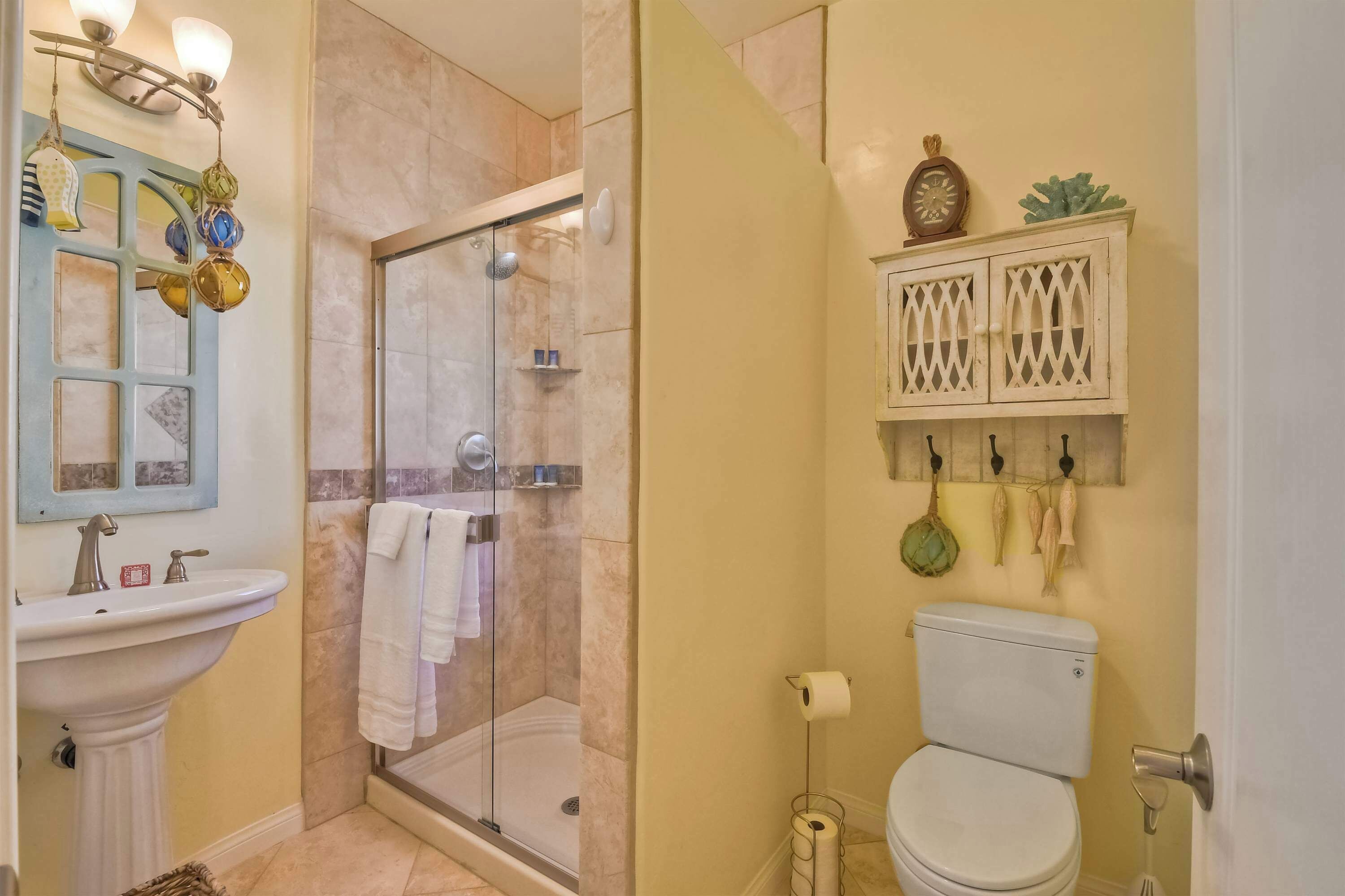 Un baño con cabina de ducha de vidrio, lavabo con espejo e inodoro.