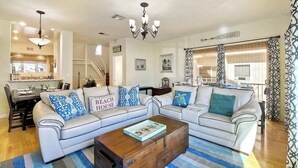 A spacious living room with a large L-shaped sofa, a wooden coffee table, and a chandelier. - South Pacific Walk to Beach! (Oceanside)