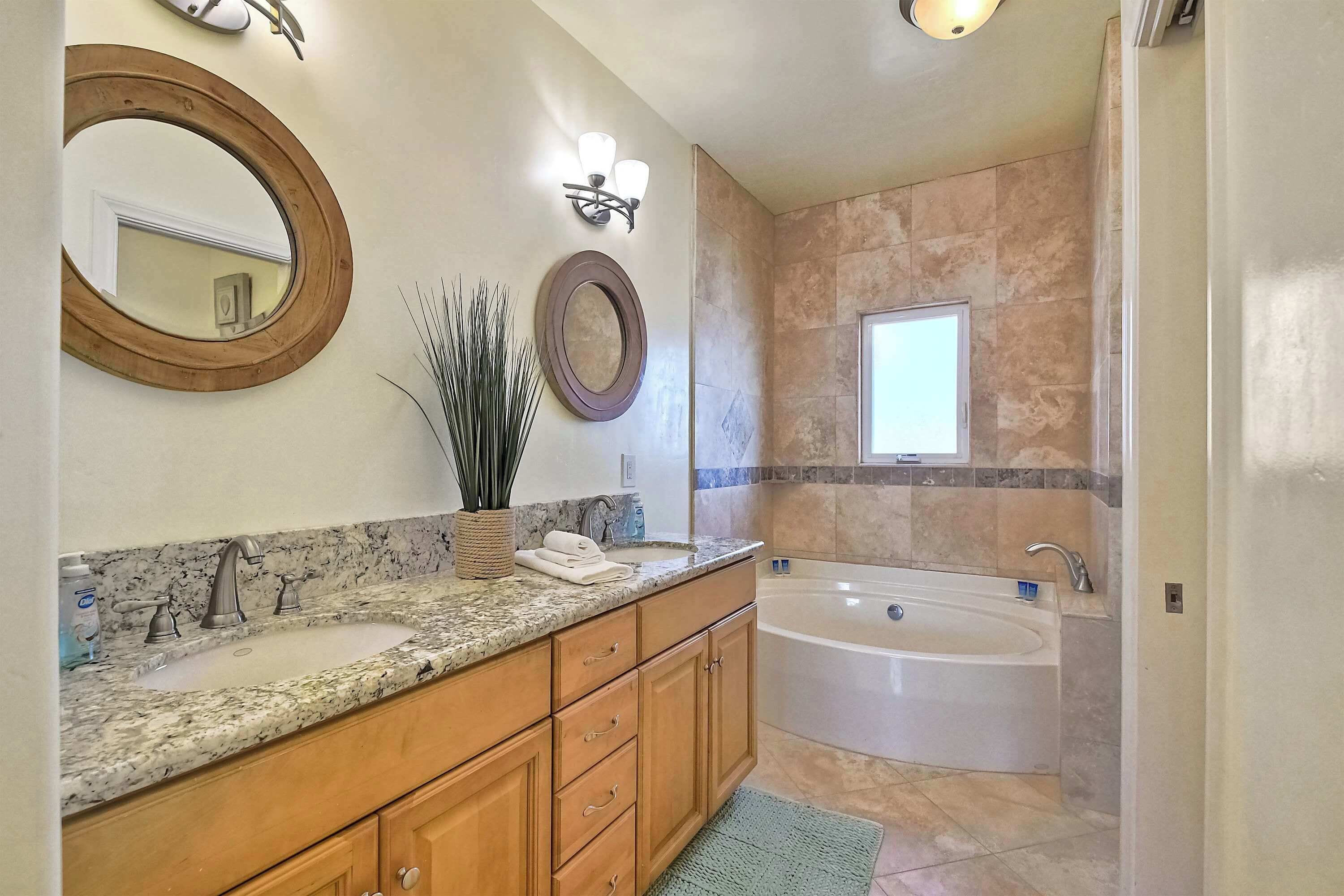 A bathroom with two sinks, a large bathtub, and a mirror.