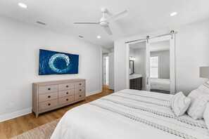 A bedroom with a bed, dresser, and a ceiling fan.