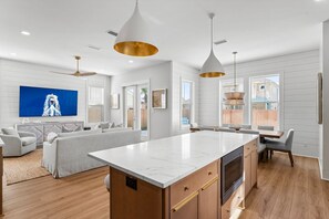 A modern kitchen with a marble countertop, wooden cabinets, and a central island. - Sunset Palms 305–Close to Gulf–Sleeps 10 (Panama City Beach)