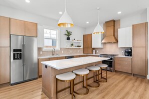 A modern kitchen with a central island, stainless steel appliances, and wooden cabinetry.