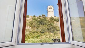 Una ventana con vista a un faro en una colina.