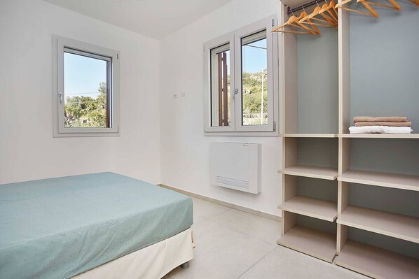 Une chambre à coucher avec un lit, deux fenêtres, un radiateur et une armoire.