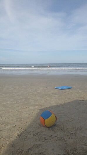 A beach with a volleyball and a blue surfboard on the sand. - House in Itapoa (Pontal do Norte Itapoá)