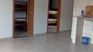 Una habitación con piso de baldosas, un ventilador de techo y dos puertas abiertas que dan a un armario con una cama.