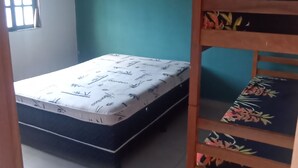 Una habitación con una cama, una litera y un ventanal con cortinas.