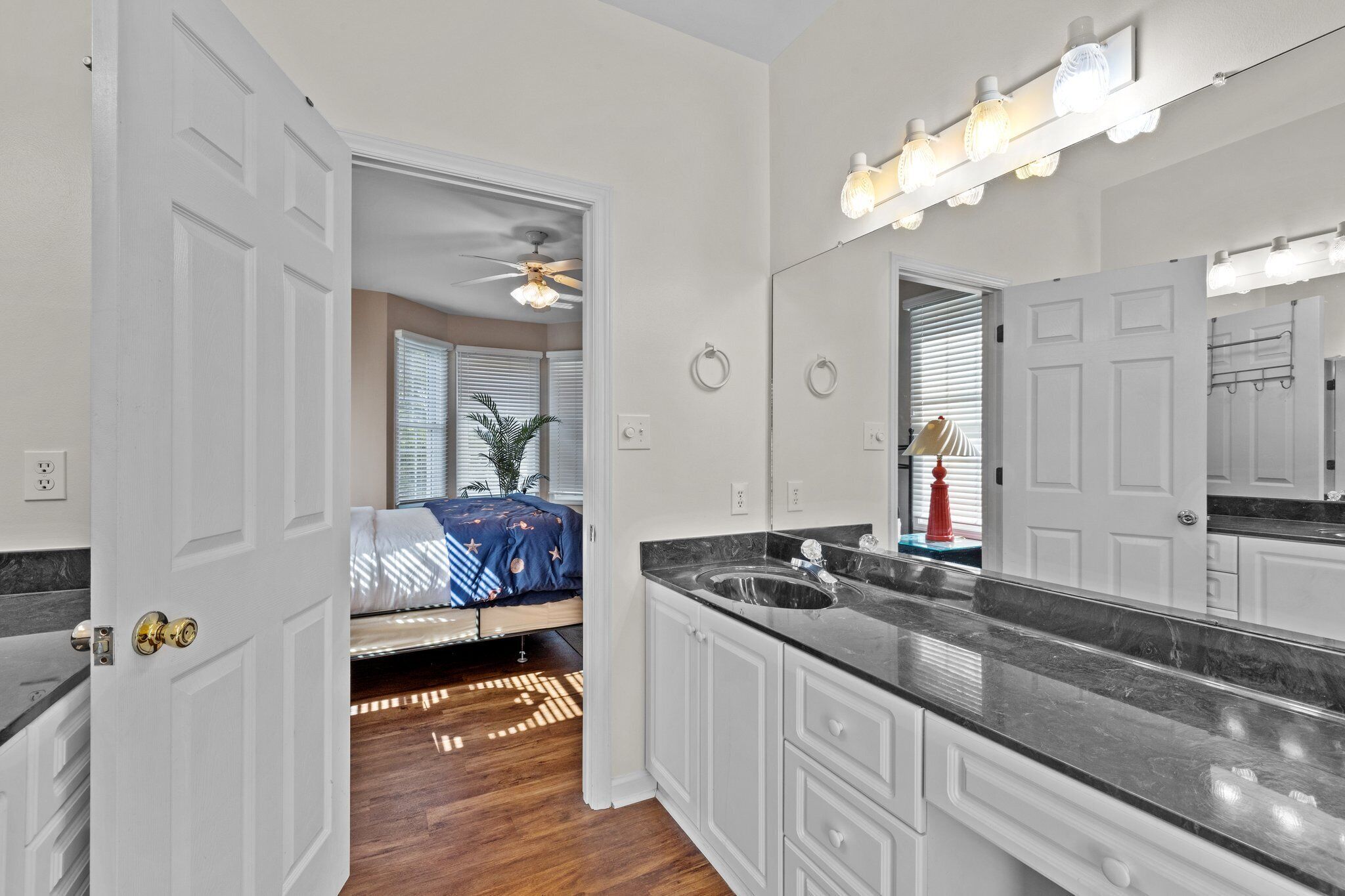 A modern bathroom with a large mirror, vanity, and a ceiling fan.