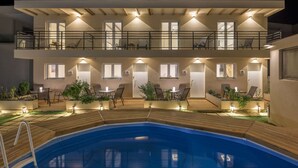 Een hotel met twee verdiepingen, een zwembad, terras en meerdere balkons.
