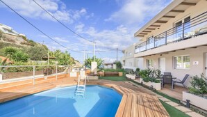 Een modern buitenzwembadgedeelte met een houten terras, een klein zwembad en een balkon met zitplaatsen.