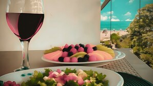 A table with a glass of red wine, a plate of colorful fruit, and a salad.