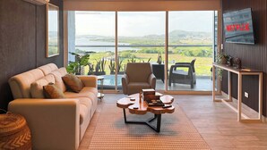 A modern living room with a sofa, armchairs, a coffee table, and a TV.